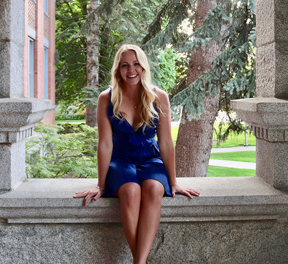 A woman stands with her arms crossed next to a window
